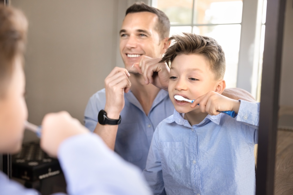Father and child brushing their teeth in front of a mirror, promoting healthy oral hygiene habits and family-focused dental care at Mira Mesa Family Dentistry - Mira Mesa Family Dentistry