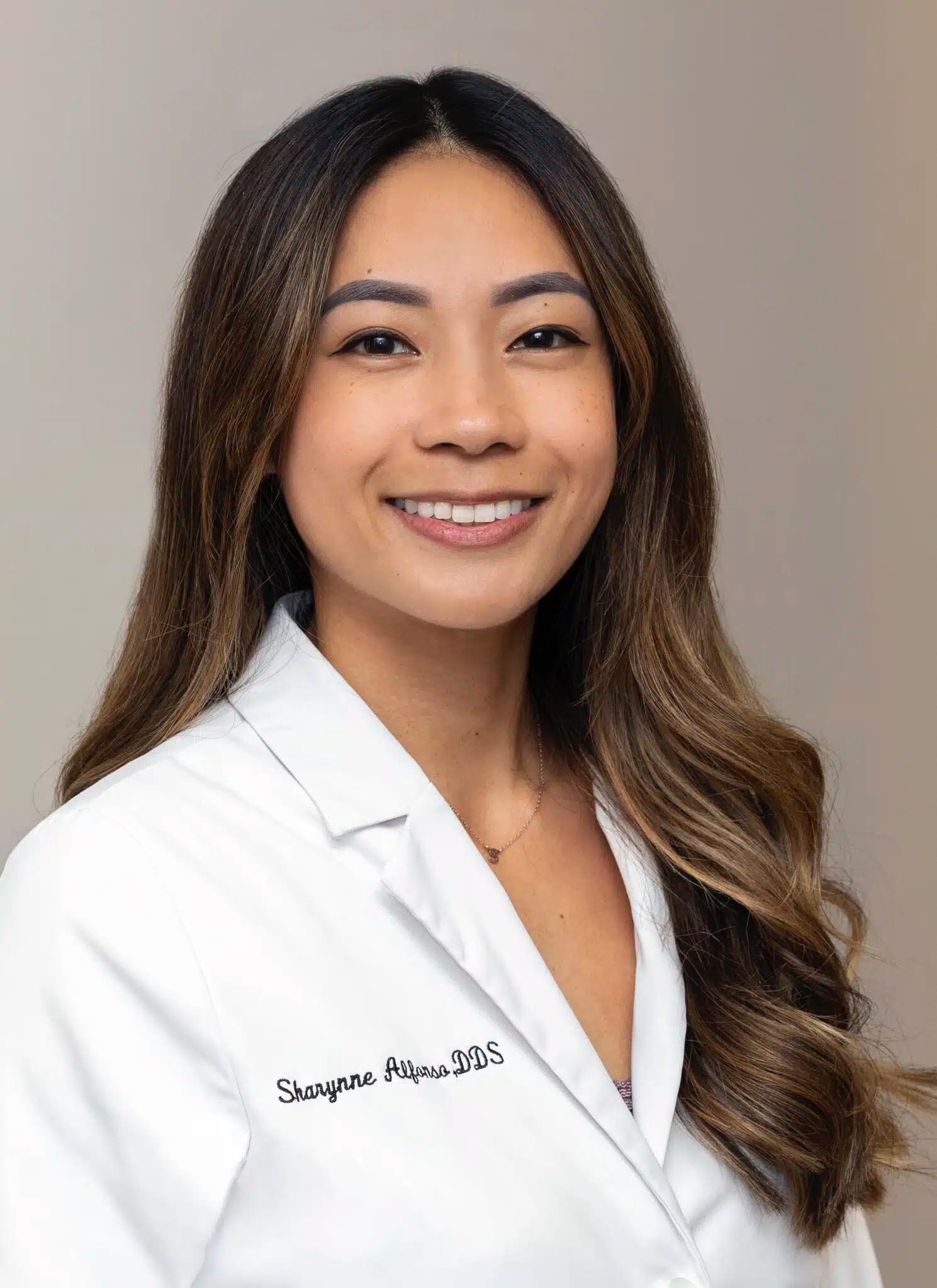 Portrait of Dr. Sharynne Alfonso DDS in a white coat smiling confidently, representing a skilled and welcoming dentist at Mira Mesa Dental - Mira Mesa Dental