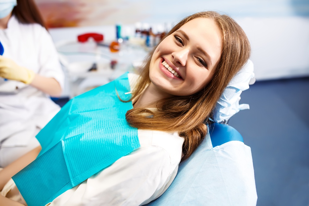 Smiling female patient sitting comfortably in a dental chair during a professional cleaning, highlighting a positive experience with San Diego teeth cleaning - San Diego Teeth Cleaning