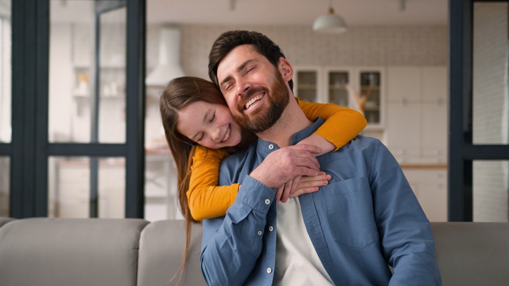 Smiling father and child embracing on a couch, showing bright, healthy smiles and representing family-focused dental care at Mira Mesa Family Dentistry - Mira Mesa Family Dentistry