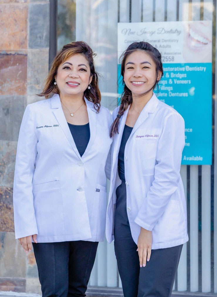 Dr. Rossana T. Alfonso and Dr. Sharynne Alfonso standing together in white coats outside their dental office, representing experienced and friendly care at Mira Mesa Dental - Mira Mesa Dental